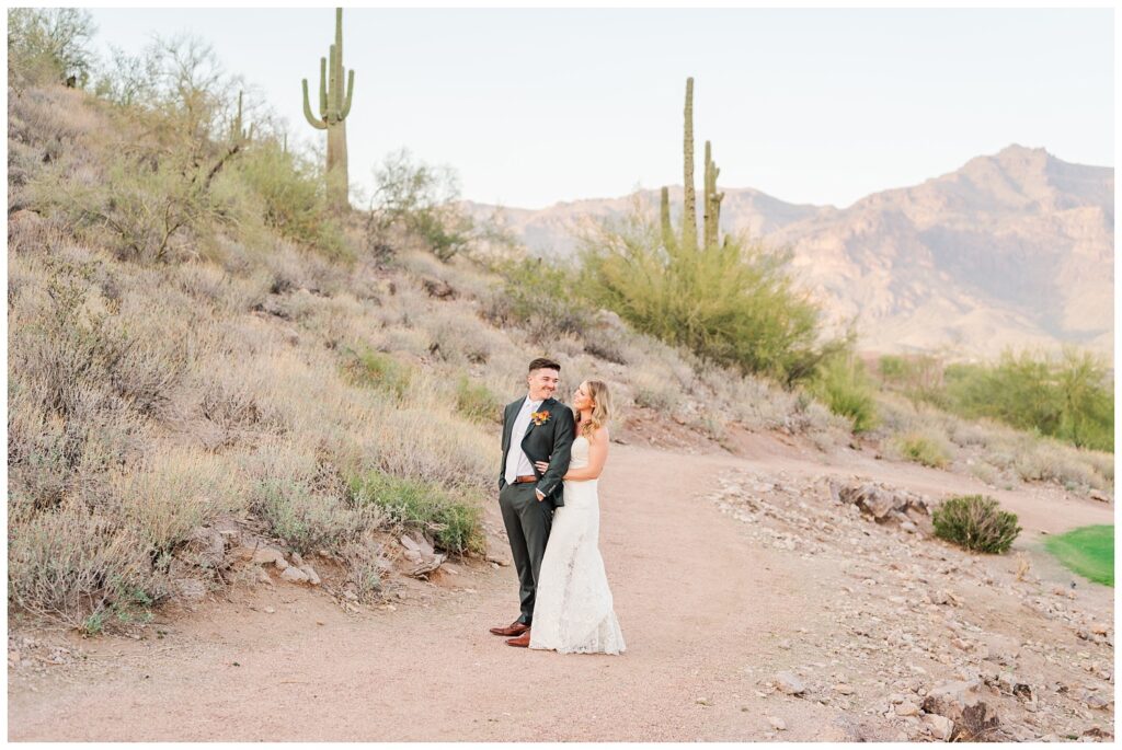 bride posing behind the groom on a trail at the Gold Canyon Golf Resort wedding venue