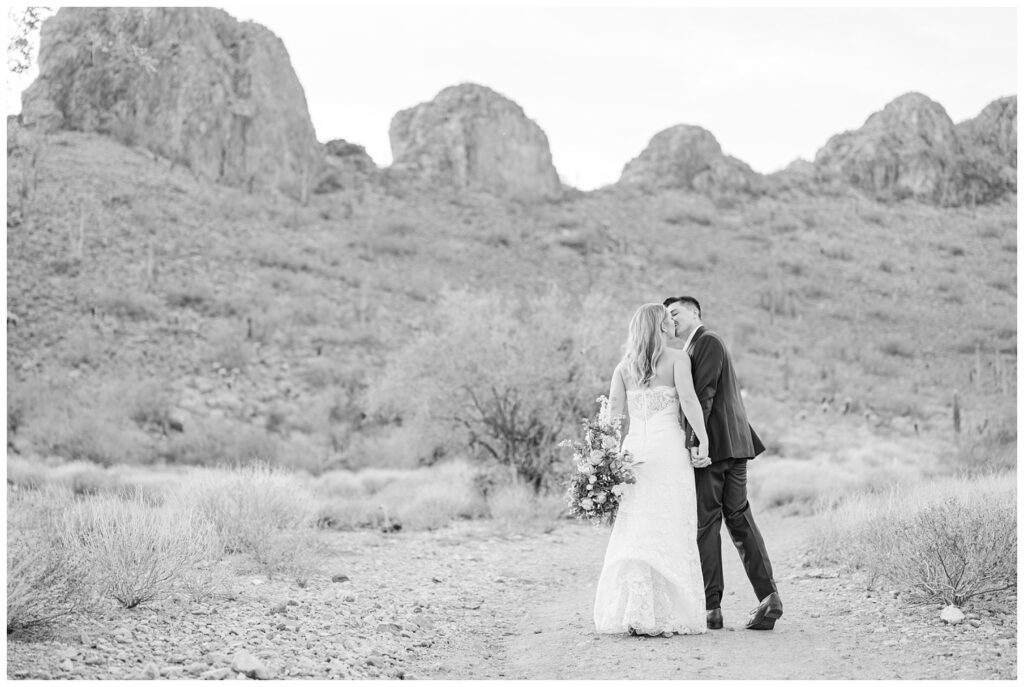 groom kissing the bride on a trail in Arizona while she carried her bouquet