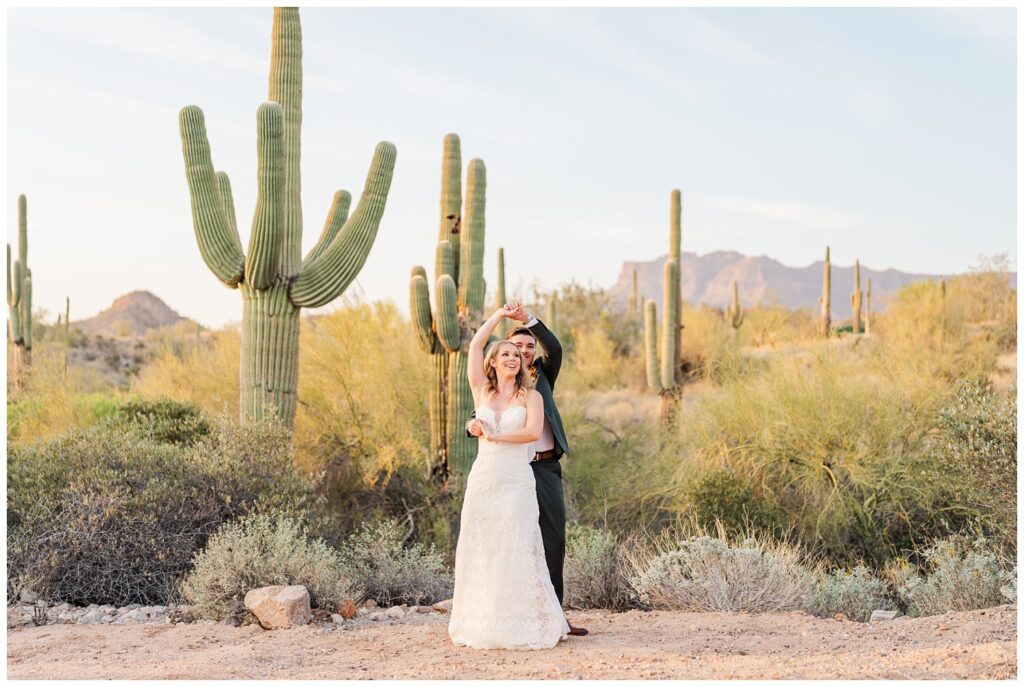 groom twirling the bride in the desert among the cacti in Arizona