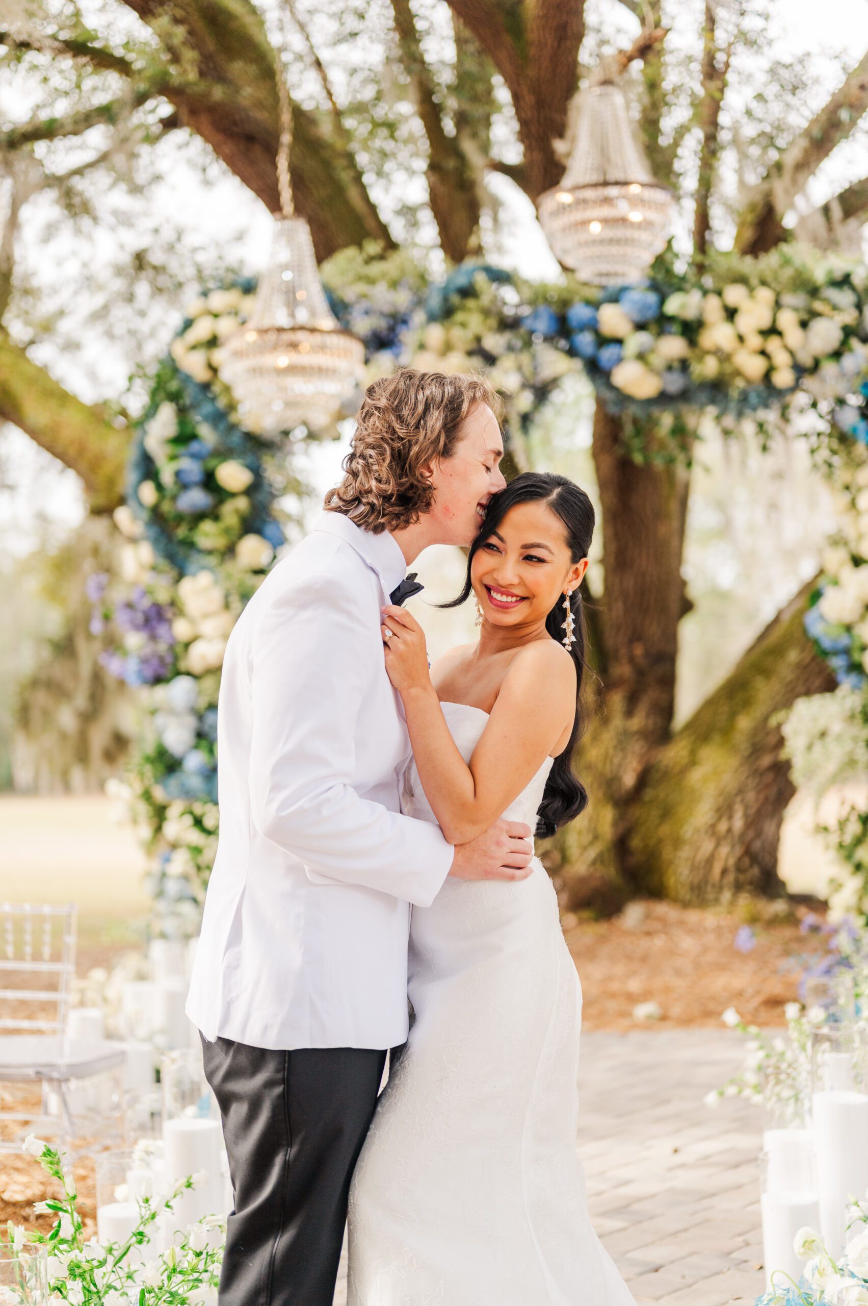 bride smiling as the groom kisses the top of her head