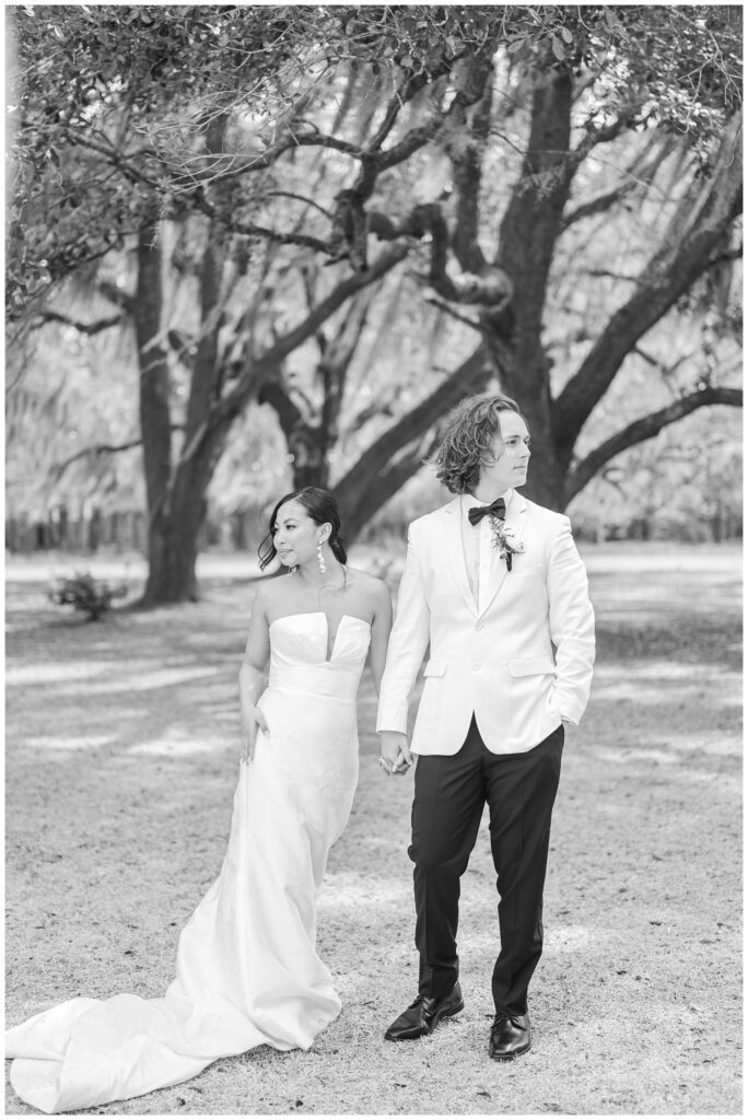 wedding couple holding hands and looking off in different directions outside 
