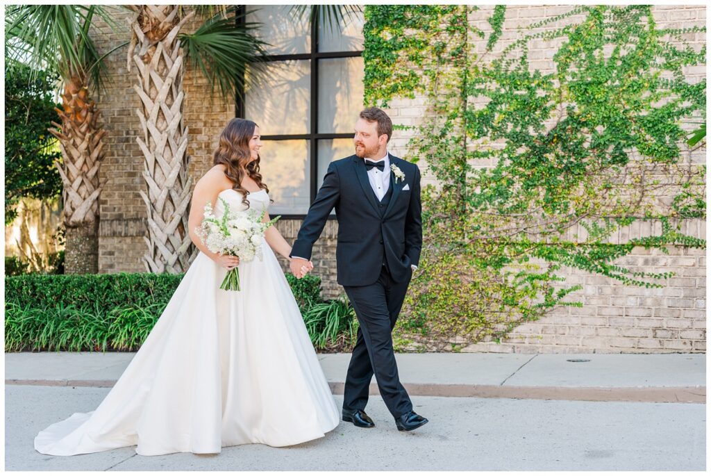 bride and groom holding hands and walking together outside the venue