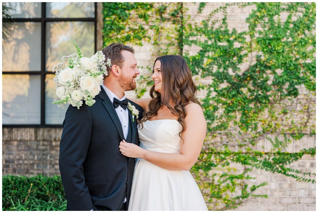 bride smiling and holding her bouquet behind the groom's head before the wedding