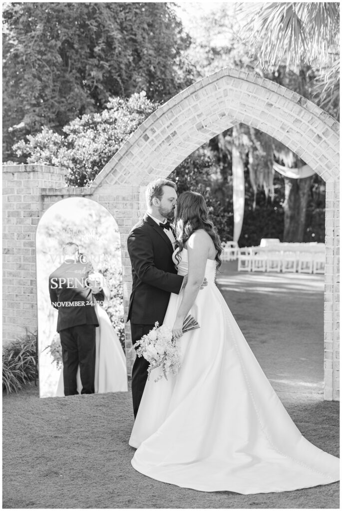 bride and groom posing in front of their hand painted mirror outside at the wedding venue 
