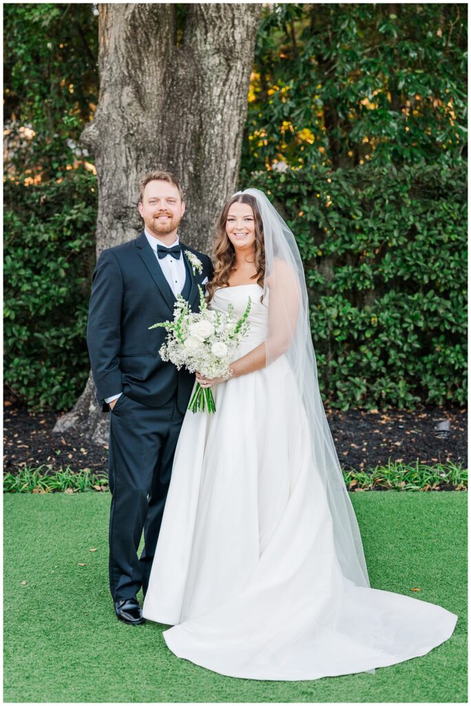 wedding couple posing together in front of the big live oak tree at Wrightsville Manor