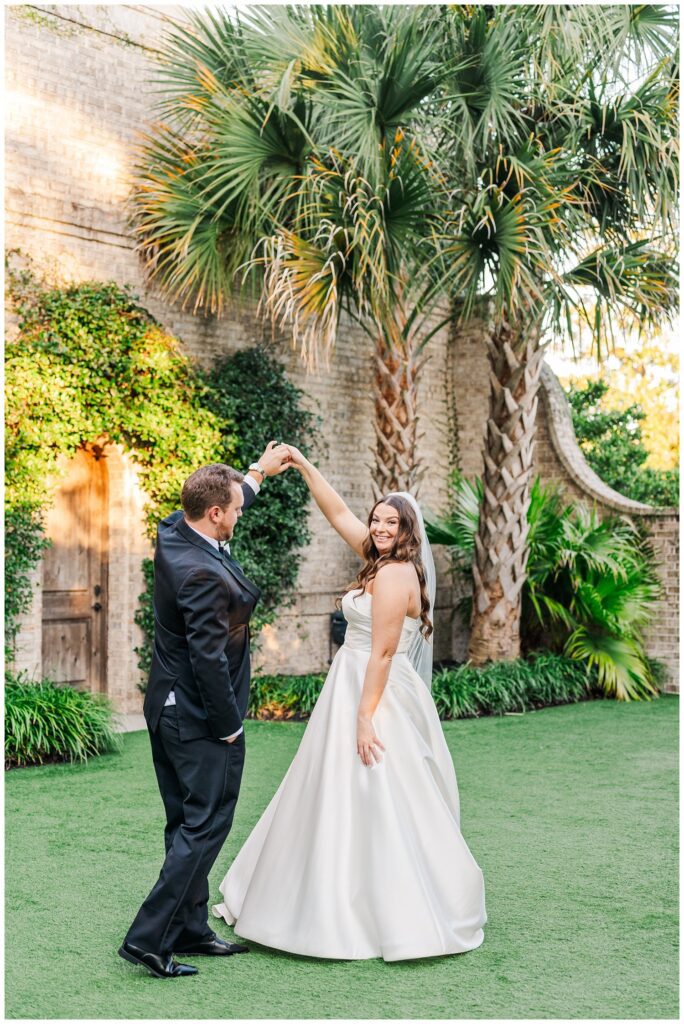 groom twirling the bride outside in front of the venue and palm trees at Wrightsville Manor