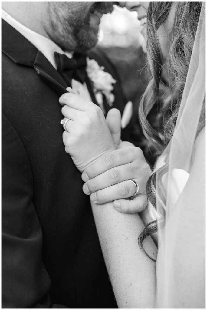close up of the groom holding the bride's arm while she is holding his lapel