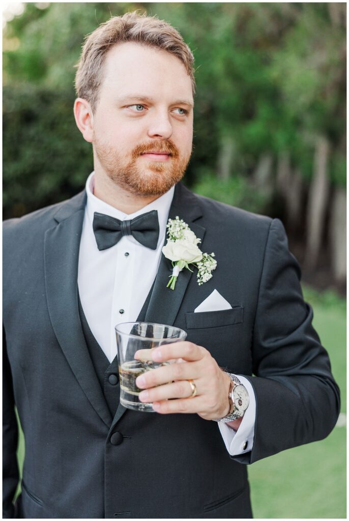 groom holding a cocktail after couples portraits at Wrightsville Manor
