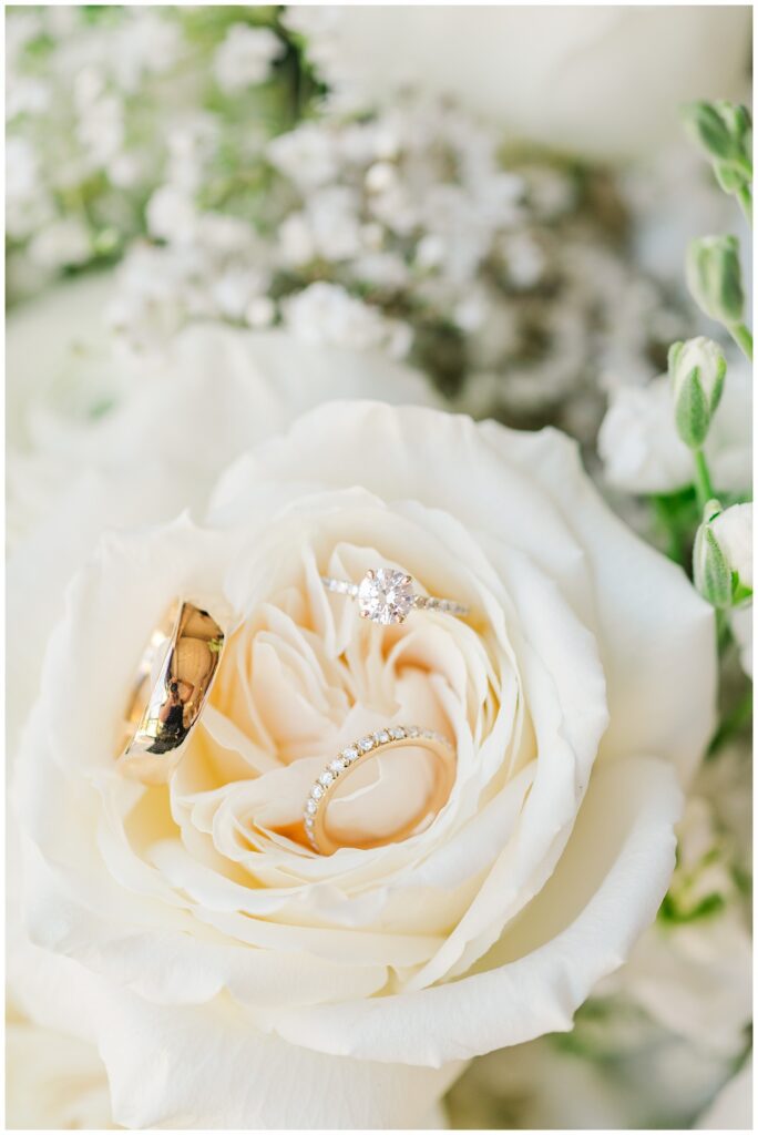 wedding rings sitting in a white rose in the bride's bouquet 