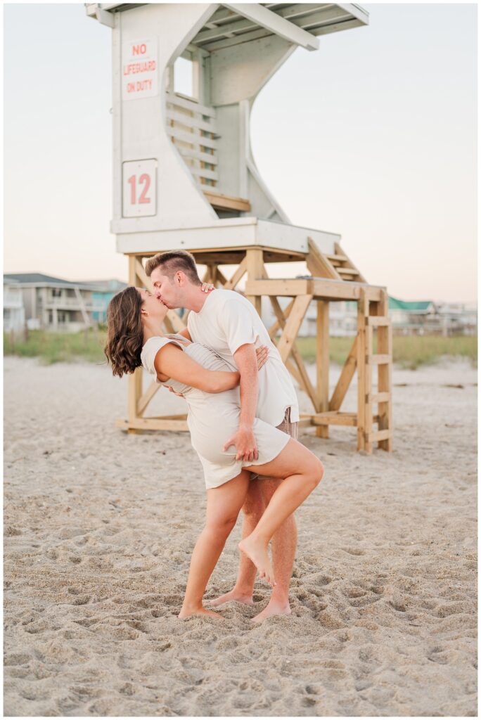 man dipping back his fiancee for a kiss on the beach in Wilmington