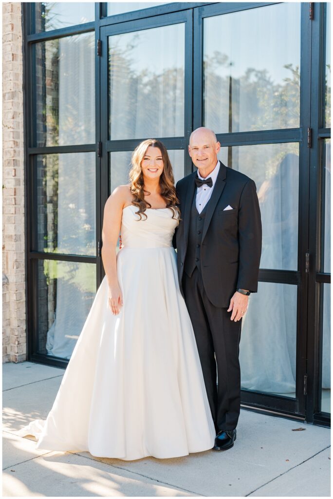 first look between the bride and her dad outside in front of large windows in Wilmington