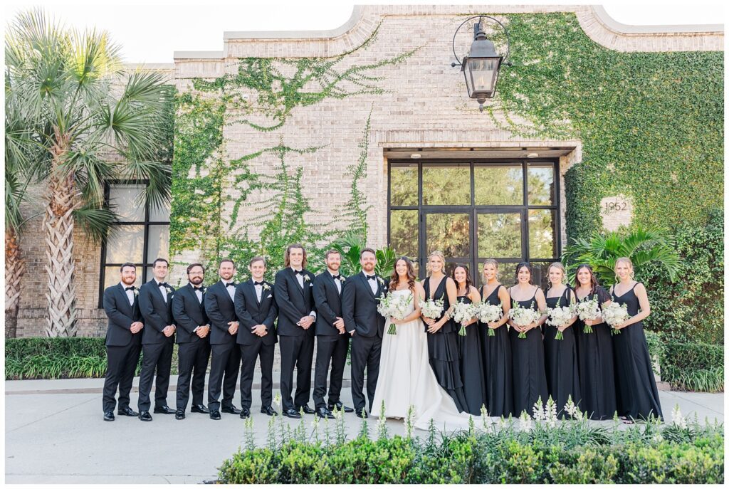 full wedding party posing together in front of the wedding venue in Wilmington