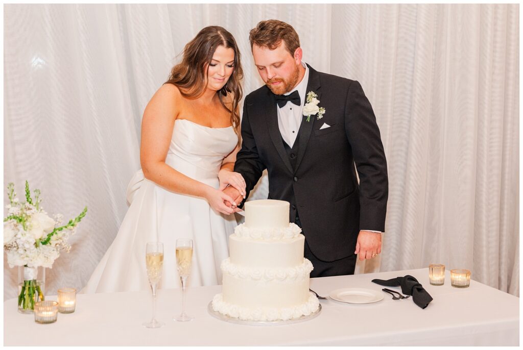 groom and bride cut cake in front of the window at Wilmington wedding venue