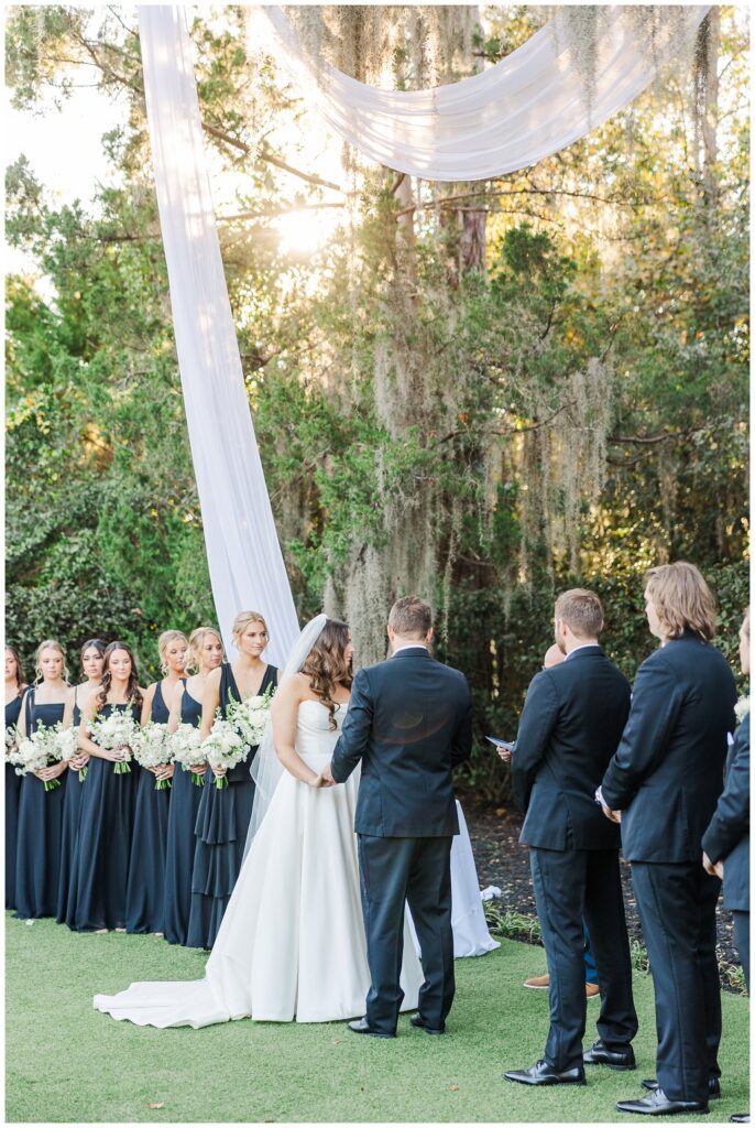 wedding couple looking at the minister during the wedding ceremony outside in front of a live oak tree
