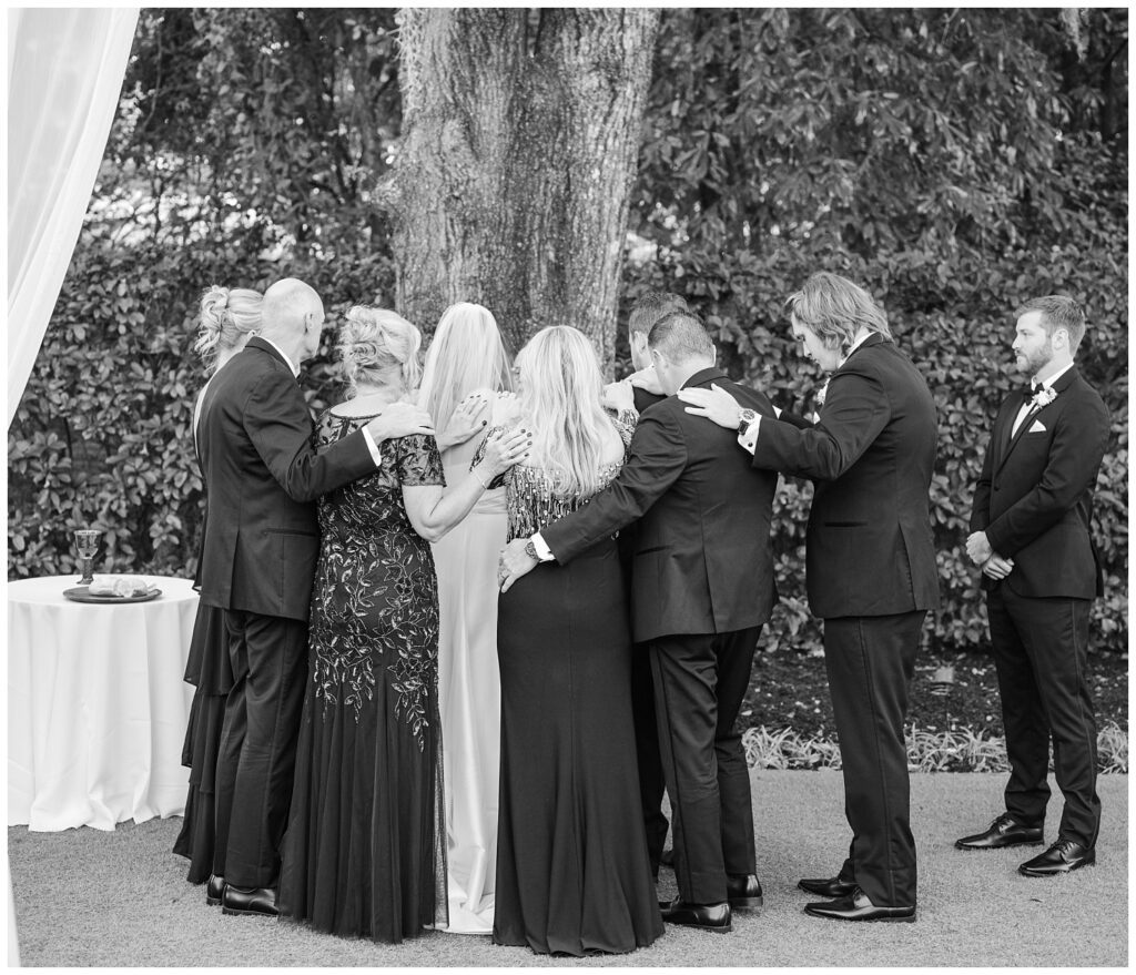family of bride and groom praying over the couple during the ceremony in Wilmington
