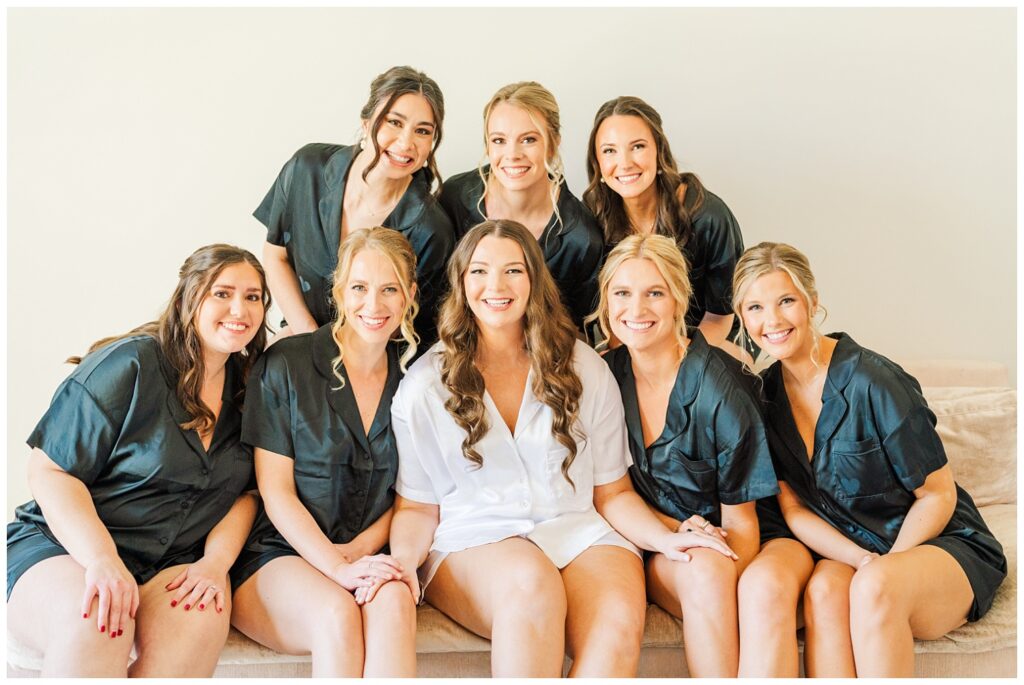 bride and bridesmaids posing with silk pajamas on the couch while getting ready