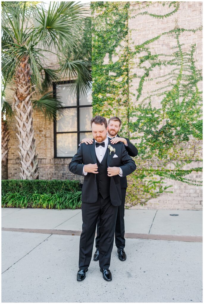 best man helping the groom put on his jacket outside at Wrightsville Manor