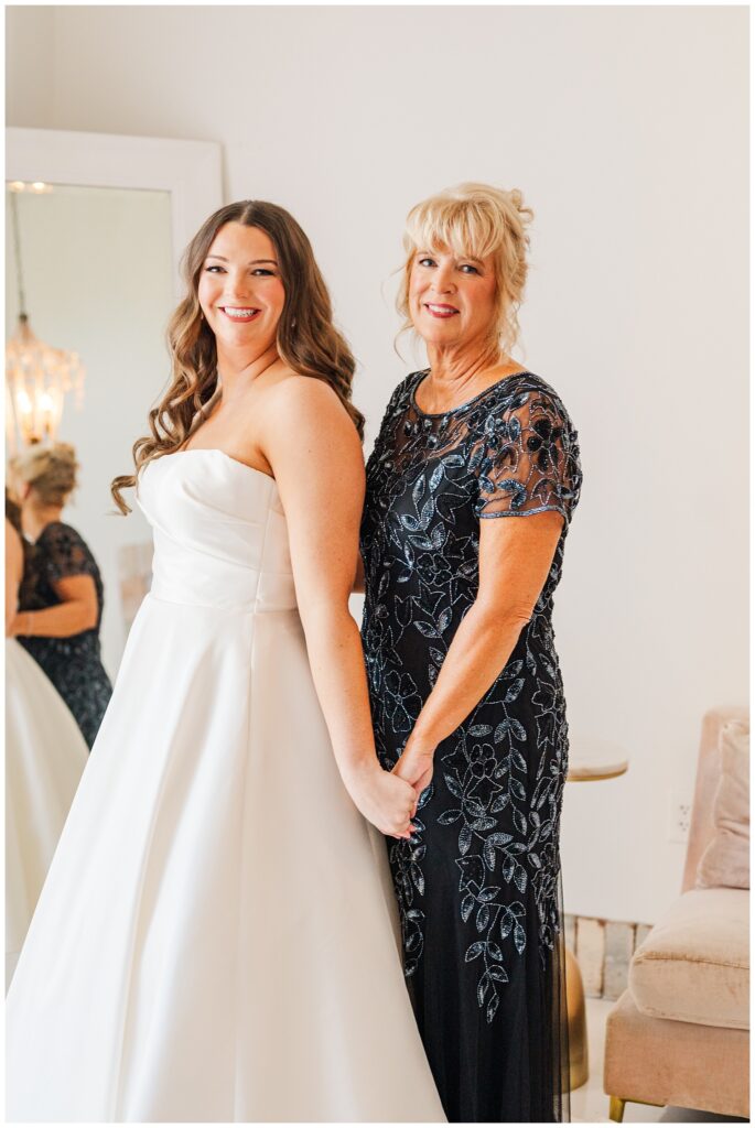 bride's mom posing with the bride while getting ready with the Wilmington wedding photographer
