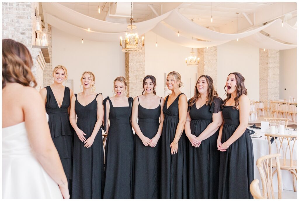 bride revealing her dress to her bridesmaids inside the reception room at Wrightsville Manor