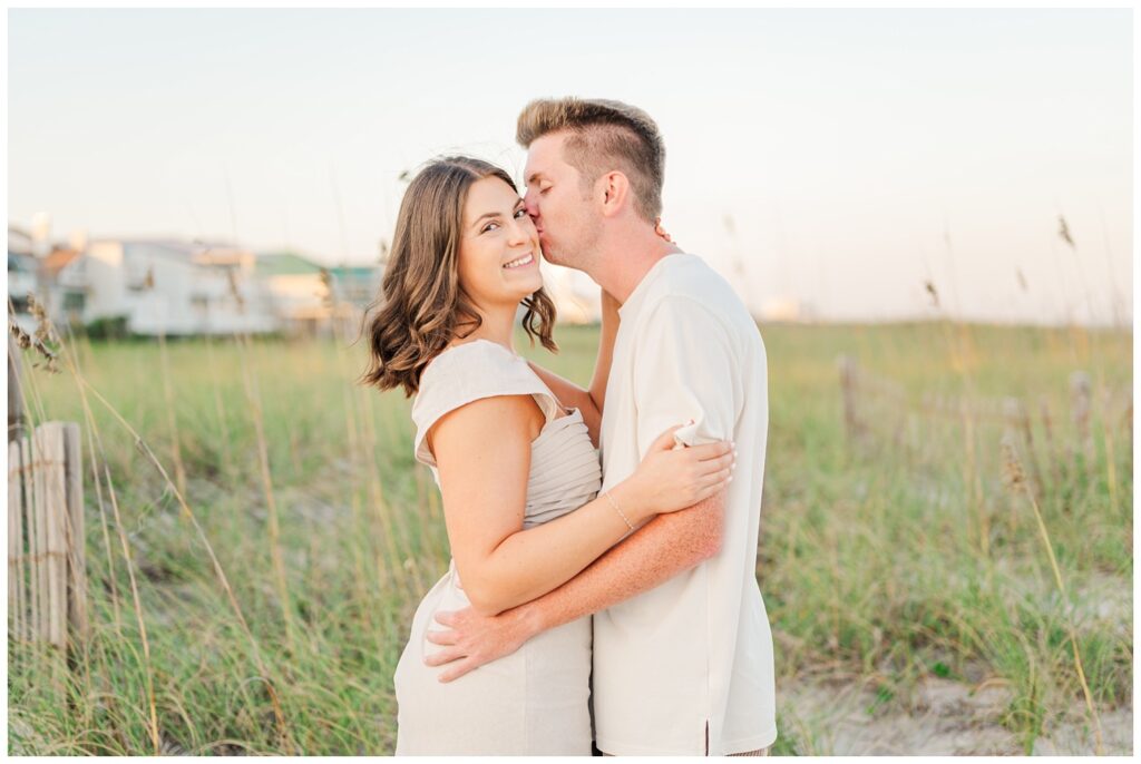 couple kissing near the beach dunes in Wilmington during golden hour 