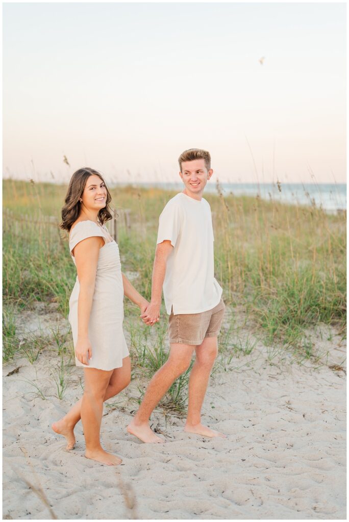couple walking together on the sand at Wrightsville Beach engagement session