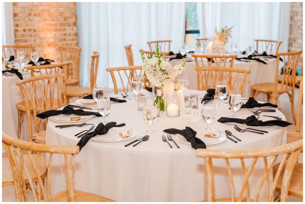 wedding reception table with white linens and black napkins and floral centerpieces 