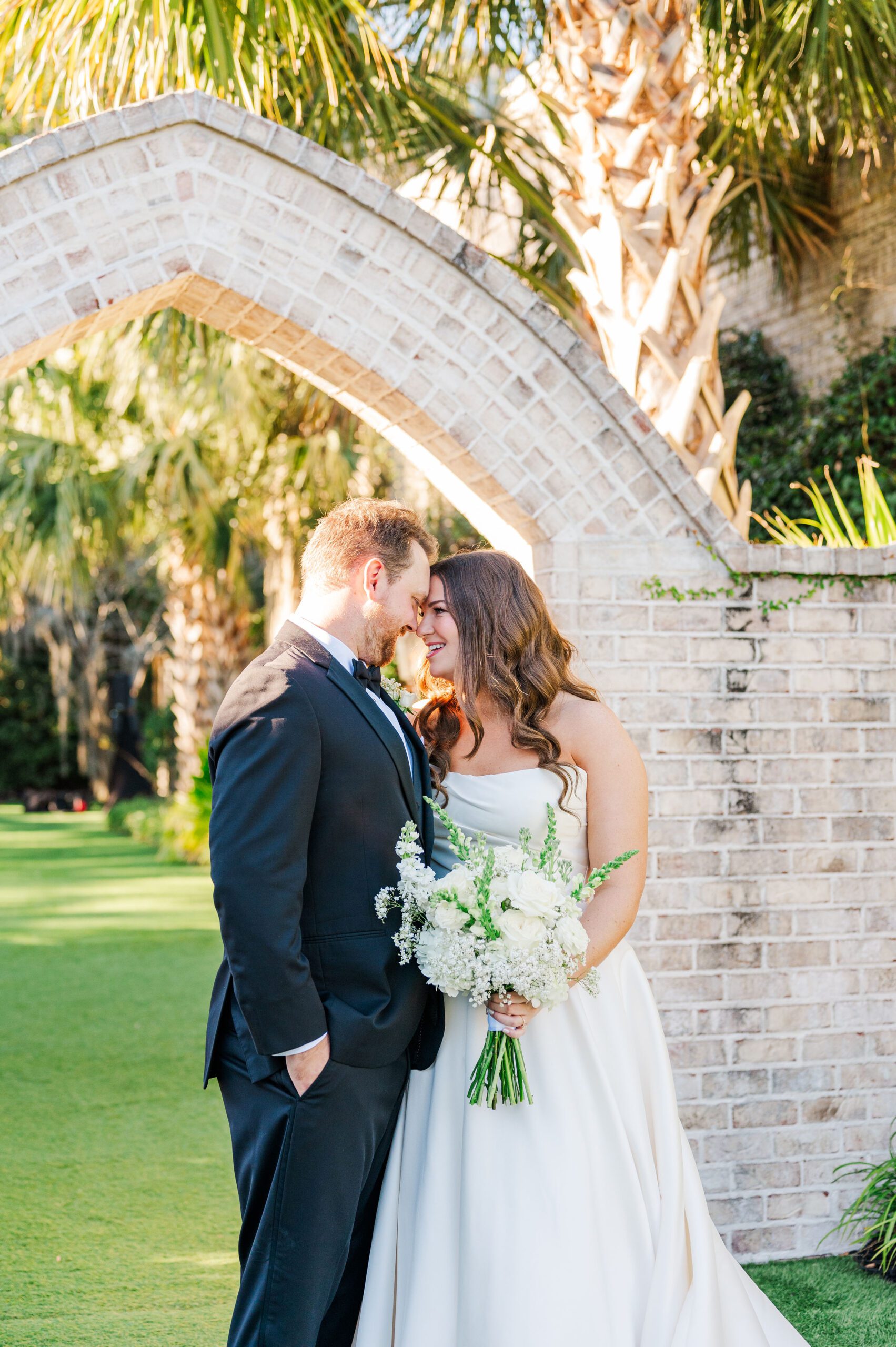 bride and groom posing in front of a stone arch in Wilmington