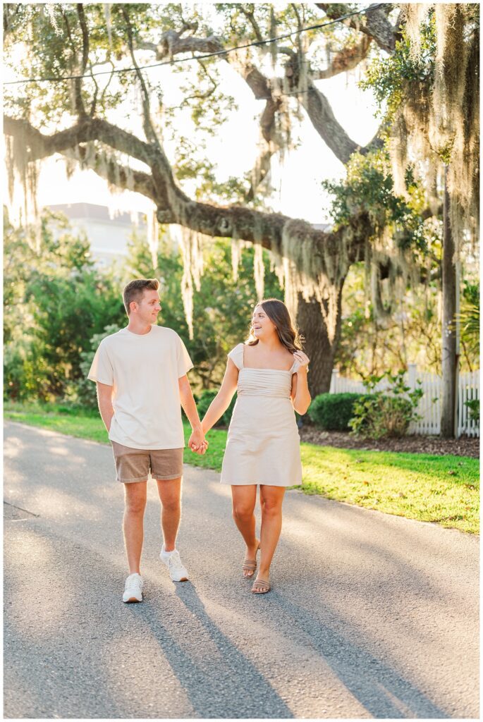 couple holding hands and walking under a big live oak in Wilmington